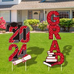 two graduation yard signs in front of a house with grass and flowers on the lawn