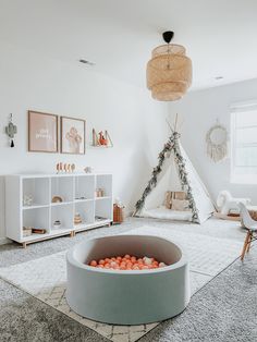 a teepee tent in the corner of a room with orange balls on the floor