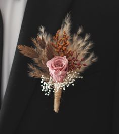 a boutonniere with flowers and feathers on it is worn by a man in a tuxedo