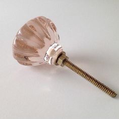 a pink glass door knob on a white surface with a screw in the middle that has been turned upside down