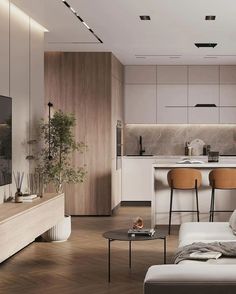 a living room filled with furniture and a flat screen tv mounted on a wall next to a kitchen