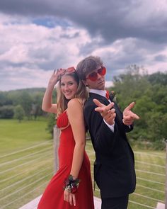 a man and woman dressed in formal wear posing for a photo on a wooden deck