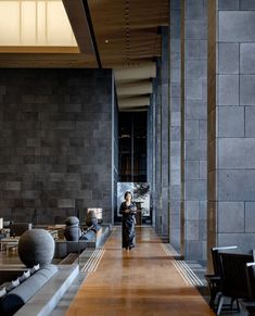 a man walking down a long hallway between two large walls with sculptures on each side