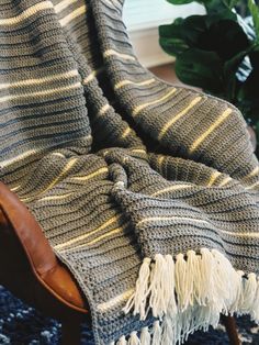 a chair with a blanket on top of it next to a potted green plant