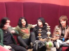 four people are sitting on a red couch