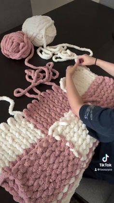 a woman is making knitted items on a table