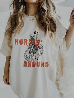 ✺ HORSIN' AROUND SKELETON GRAPHIC TEE ✺  * Q U I C K F A C T S * ✺ 100% Cotton (fiber content may vary for different colors) ✺ Classic fit ✺ Sizing is unisex so runs like men's, though not overly large ✺ Most women find their typical size works best, since they are meant to fit a touch loose Please note that colours may appear different on different digital screens and may not be a true representation of the actual colours. * KEEP SHOPPING * ✺ NASHVILLE SAND TEE WITH BLACK PRINT : https://www.et Cute Western Shirts, Western Skeleton, Oversize Graphic Tee, Country Graphic Tees, Country Outfit, Trendy Shirt Designs, Western Graphic Tees, Country Music Shirts, Vibe Check