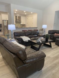 a living room with couches, chairs and lamps on the floor in front of an open kitchen