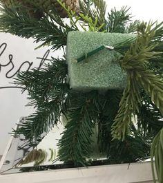 a green towel hanging from a christmas tree with pine cones and needles on it's side