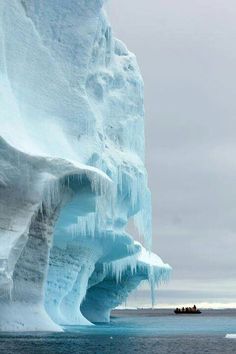 an iceberg with people in a small boat on the water