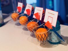 oranges in baskets with name tags on them sitting on a table next to bottles