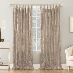 a living room with a white chair and beige curtains on the window sill in front of it