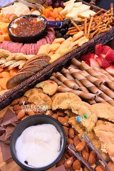 an assortment of snacks and dips on a wooden platter with chocolate chips, strawberries, almonds