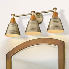 three light bathroom fixture with wooden accents in an antique brass finish on a white wall