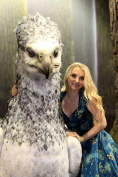 a woman is posing with an owl statue