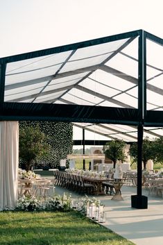 an outdoor wedding venue with white drapes and tables set up for the guests to eat