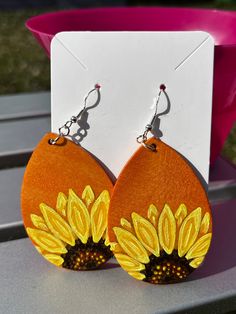 a pair of sunflower earrings sitting on top of a table