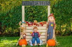 a young boy sitting on top of a wooden bench next to pumpkins and decorations