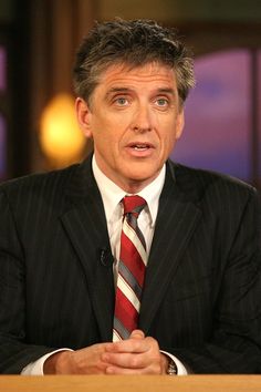 a man in a suit and tie sitting at a table with his hands folded out