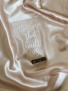 the love that guilt us is written in white ink on a satin fabric with a pen