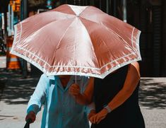 two people are walking down the street with an umbrella over their heads and one is holding a cane