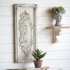 a white shelf with two potted plants on top of it next to a wall mounted mirror