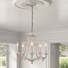 a chandelier hanging from the ceiling in a room with windows and white walls