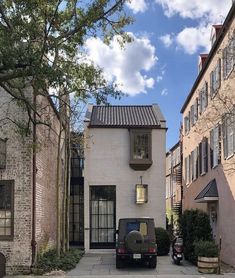 a car parked in front of a house on a street with brick buildings and trees