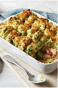 a casserole dish with chicken, broccoli and cheese in it next to a spoon