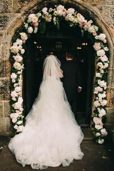 the bride and groom are standing in front of an archway