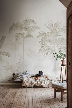 a dog laying on a bed in front of a wall with palm trees