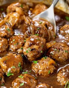 meatballs and gravy in a skillet with a spoon