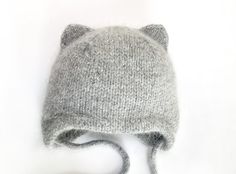 a gray knitted hat with ears is shown on a white surface, and the top part of the hat has been turned upside down