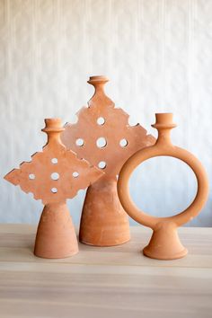 three clay vases sitting on top of a wooden table with holes in the middle