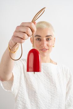 a woman holding a red light in front of her face with the cord attached to it