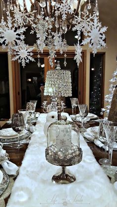 a dining room table set for christmas dinner with silverware and crystal chandelier