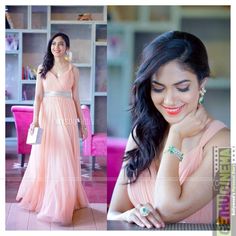 a woman in a long pink dress posing for the camera and holding her hand on her shoulder