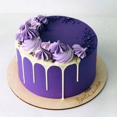 a purple cake with white icing and flowers on top