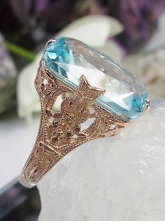 Simulated Aquamarine Rose Gold plated Sterling Silver Ring Treasure Design#D202 This is an Edwardian era reproduction filigree ring. The Art Deco design is beautifully created in rose gold plated solid sterling silver. This is a flawless man-made/simulated sky blue aquamarine that measures 18mm by 13mm. The ring is 3/4" (19mm) North to South on the finger. The inside of the band is etched 925 (sterling). Notice the intricate and detailed floral design. The rose gold 'embraced' silver filigree ac Ornate Rose Gold Jewelry With Intricate Design, Ornate Rose Gold Filigree Jewelry, Ornate Hallmarked Rose Gold Jewelry, Gold Topaz Ring With Intricate Design As Gift, Gold Topaz Ring With Intricate Design For Gift, Ornate Rose Gold Jewelry For Anniversary, Heirloom Style Filigree Ring With Intaglio For Gift, Rose Gold Filigree Jewelry For Anniversary, Heirloom Filigree Ring With Intaglio For Gifts