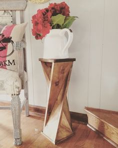 a vase with flowers sitting on top of a wooden table next to a white chair