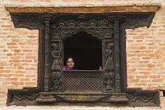 a woman is looking out the window of an old brick building with carved ironwork