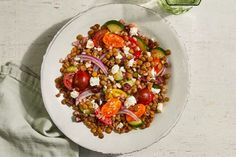 a white bowl filled with beans, tomatoes and cucumbers