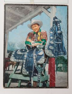 a man sitting on top of a wooden bench next to a blue horse statue in front of a white building