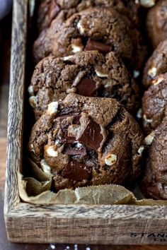 chocolate chip cookies in a wooden box with white and brown toppings on the top