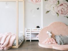 there is a pink bed with flowers on the wall next to it and a stuffed animal