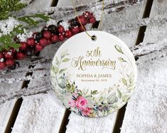 a 50th anniversary ornament hanging on a wooden table with berries and greenery