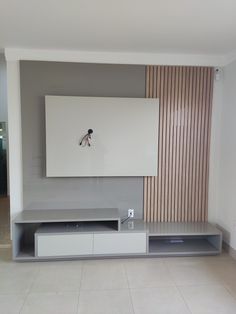 an empty room with a large flat screen tv on the wall and shelves below it