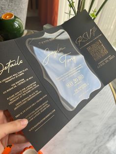 a person holding up a black and gold wedding program