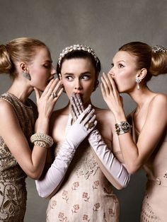 three beautiful women in dresses and jewelry posing for the camera with their hands on their mouths