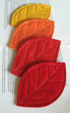 three pieces of felt sit on top of an open book, each with different colored leaves